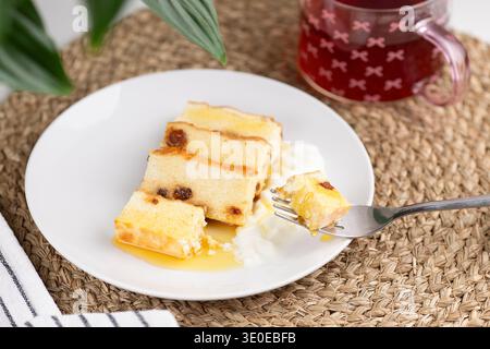 Blick von oben auf einen hausgemachten Hüttenkäseauflauf mit Rosinen auf einem weißen Teller, serviert zum Frühstück auf einem rustikalen Holztisch. Stockfoto