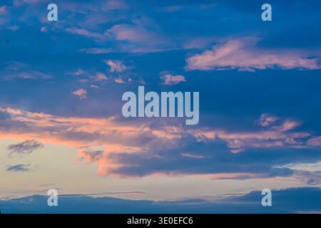 Eine wunderschöne Dämmerungsszene mit tiefblauer Atmosphäre, die von zarten Wolken mit warmem Orange und Rosa beleuchtet wird. Stockfoto