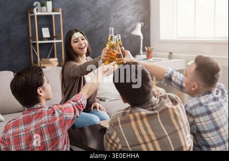 Glückliche junge Freunde, die Bierflaschen anstoßen Stockfoto