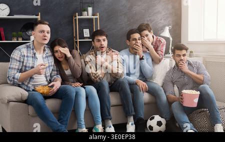 Schockierte multiethnische Freunde, die zu Hause Filme sehen Stockfoto
