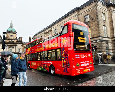 Edinburgh, Schottland, Vereinigtes Königreich - 15. Februar 2026: Roter Doppeldeckerbus fährt vorbei an gewölbten historischen Gebäuden im verregneten Edinburgh inmitten wartender Sehenswürdigkeiten Stockfoto