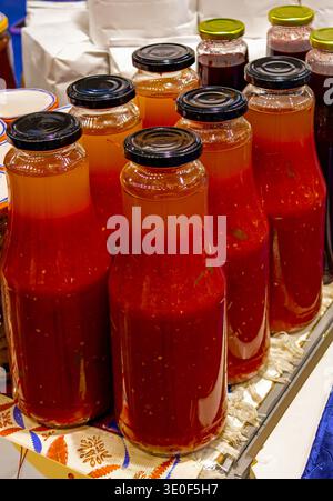 Rote Tomatensäfte aus biologischem Anbau in Glasflaschen in der Wohnküche Stockfoto