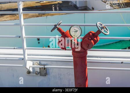 Nahaufnahme des roten Hydranten mit Manometer in der Nähe des weißen Geländes auf der Gebäudeterrasse. Miami Beach. USA. Stockfoto