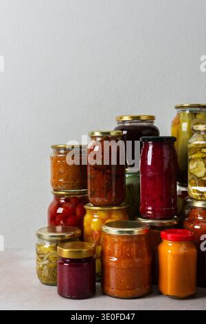 Canning ist eine häufige Aktivität in der Küche, da die Theke mit Gemüse und Obst gefüllte Gläser säumen. Diese Praxis hilft dabei, Lebensmittel für den Gewinn zu bewahren Stockfoto