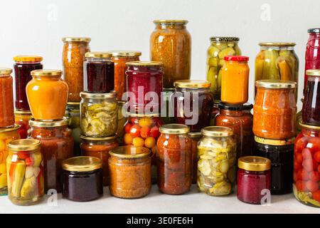 Gemüse- und Obstkonserven werden auf einem Regal für den Wintergebrauch vorbereitet. Verschiedene Gläser enthalten verschiedene Konserven, was die sorgfältige Lagerung von Lebensmitteln während der Saison zum Ausdruck bringt Stockfoto