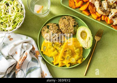Genießen Sie ein lebhaftes Frühstück mit Rührei mit Rhabarber, flauschigen Quinoa-Pfannkuchen, cremiger Avocado mit Olivenöl, geröstetem Gemüse und einem erfrischenden frischen Salat Stockfoto