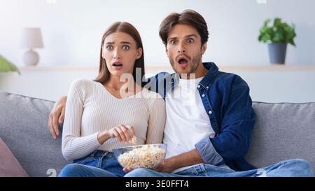 Überraschungsmoment, den ein Paar bei einem Film zu Hause am Abend mitteilt Stockfoto