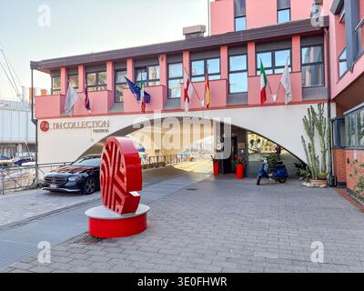 Eingang zum NH Collection Marina Hotel. Genua, Italien. Mit italienischen Flaggen, EU-Flaggen, Skulpturen und geparkten Rollern in der Nähe des Yachthafens. Stockfoto