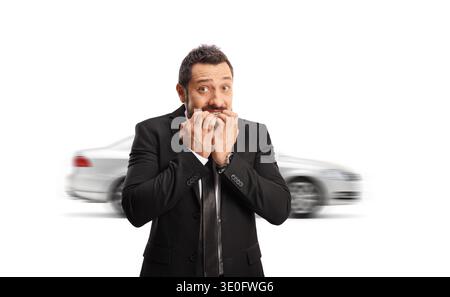 Nervöser Mann, der Nägel beißt und ein rasendes Auto auf weißem Hintergrund betrachtet Stockfoto