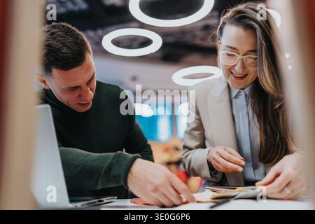 Zwei Kollegen arbeiten an einem hellen Bürotisch zusammen, prüfen Dokumente und diskutieren Ideen Stockfoto