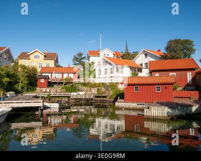 Häuser und Bootshäuser am Wasser im Hafen von Gullholmen auf der Insel Härmanö, Bohuslän-Archipel, Westküste Schwedens Stockfoto