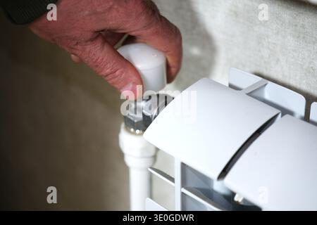 Nahaufnahme einer Hand, die ein Kühlerventil dreht und den Durchfluss von heißem oder kaltem Wasser reguliert. Stockfoto