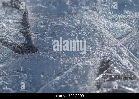 Körniges Frühlingseis weist bläuliche Kanten auf. Das Frühlingseis hat eine grobe Textur mit Körnung und zarten blauen Highlights entlang der Grenzen Stockfoto