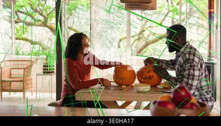 Ein Paar in kariertem Hemd und rotem Pullover schnitzt zwei Kürbisse auf der Sonnenterrasse mit Werkzeugen. Herbstlich, rustikal, Tageslicht, gemütlich, Basteln, gemeinsam Stockfoto