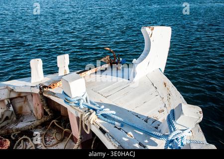 Traditioneller hölzerner Fischerbootbogen, der im ruhigen mediterranen Hafenwasser verankert ist und maritimen Lebensstil, Reisen und Küstenkultur repräsentiert. Stockfoto