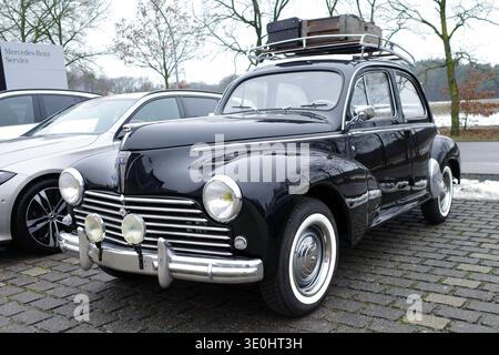 Itterbeck, Deutschland - 13. Januar 2026 die Vorderseite eines alten schwarzen Peugeot 203 C mit Koffern auf dem Dach. Der Wagen ist von 1955 Stockfoto