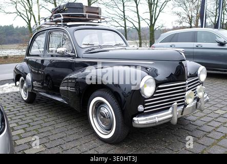 Itterbeck, Deutschland - 13. Januar 2026 die Vorderseite eines alten schwarzen Peugeot 203 C mit Koffern auf dem Dach. Der Wagen ist von 1955 Stockfoto