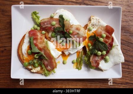 Offene Sandwiches mit Spiegeleiern, Speck und Erbsen Stockfoto