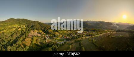 'Luftpanorama eines abgelegenen bosnischen Dorfes umgeben von Dinarischen Bergen bei Sonnenuntergang, Bosnien und Herzegowina' Stockfoto