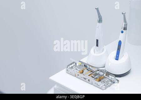 Moderne Zahnhandstücke, Spritze und Instrumentenschale aus Metall auf weißem Schrank in der Klinik. Das Konzept der professionellen Mundpflege, Hygiene und des fortgeschrittenen Zahns Stockfoto