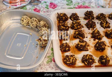 Hausgemachte Schokoladen-Nuss-Cluster oder Trüffel auf einem Tablett und in einem Plastikbehälter, auf einer Blumentischdecke, Küchen-Backszene, süße Dessertzubereitung Stockfoto