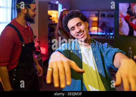 Junger Mann lächelt und tanzt auf der Hausparty mit Freunden Stockfoto