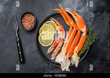 Premium alaska King Krabben Fisch und Meeresfrüchte mit Zitrone und Thymian auf schwarzem Schälchen mit dunkler Steinoberfläche im Restaurantstil Stockfoto