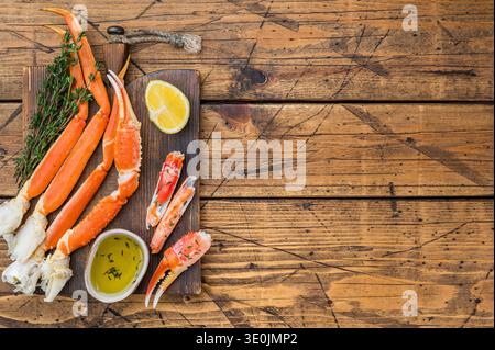 Hochwertige rote kamtschatka-Krabbenbeine, gedämpft und mit Buttersauce auf dunklem hölzernem Hintergrund, Meeresfrüchte Delikatesse Stockfoto