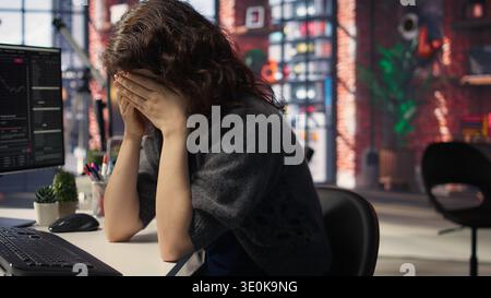 Börsenexperte ist besorgt und enttäuscht über den Börsencrash, verfolgt Finanztrends auf ihrem PC und weint. Eine Frau, die verärgert und über Geldverluste am Boden liegt. Kamera A.. Stockfoto