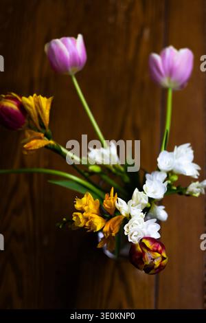 Frühlingstulpen und Freesie Blumen Blumenstrauß auf hölzernem Hintergrund, ästhetisches florales Stillleben Stockfoto