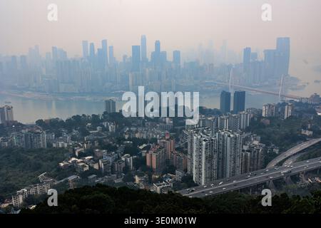 Chongqing Stadtlandschaft mit Hochhäusern, Fluss und Brücke unter einem trüben Himmel, die die städtische Dichte in china zeigt Stockfoto