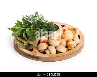 Holzteller mit leckeren Pilzen in Dosen, Dill, Petersilie und Lorbeerblättern auf weißem Hintergrund Stockfoto