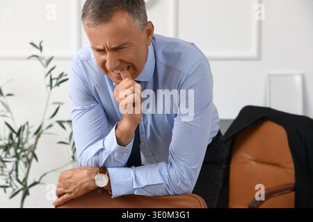 Besorgter reifer Geschäftsmann beißt Nägel im Büro Stockfoto