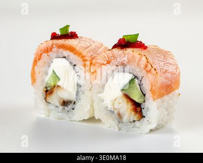 Eine Nahaufnahme von zwei japanischen Uramaki-Sushi-Brötchen mit gebratenem Lachs, Aal, Frischkäse, Gurke. Garniert mit rotem Tobiko-Reh. Saubere, minimalistische Komposition Stockfoto