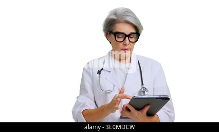 Reife Ärztin, die medizinische Informationen auf Tablette überprüft Stockfoto