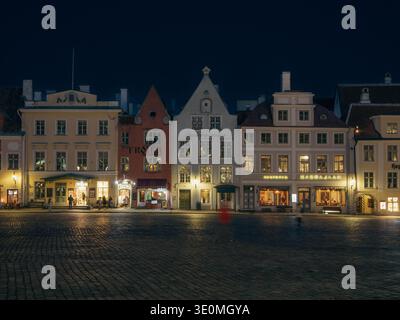 Beleuchtete mittelalterliche Kaufmannshäuser, darunter Troika-Restaurants, die in der Nähe des Rathausplatzes von Tallinn liegen, im Winter nachts Stockfoto