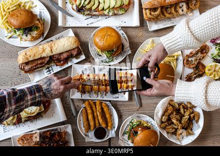 Freunde, die zusammen essen und vor dem Essen ein Foto von dem Essen machen Stockfoto