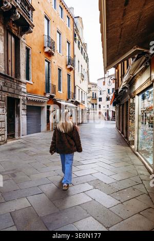 Frau läuft tagsüber in einer ruhigen Straße in Venedig Stockfoto