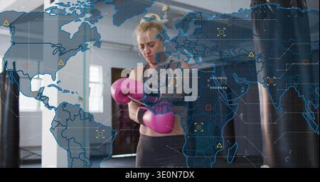Frau in Sportbekleidung, die rosa Handschuhe im Boxstudio mit Handgelenkumschlag und digitaler Karte befestigt Stockfoto