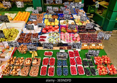 Ein Marktstand in Wien zeigt viele frische Früchte und Nüsse zum Verkauf. Käufer können aus Beeren, Trauben und anderen Produkten wählen. Stockfoto