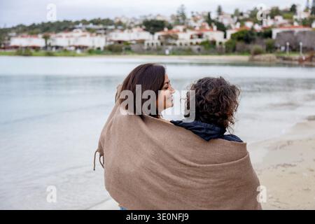 Zwei Weibchen in eine braune Decke gewickelt am Strand Stockfoto