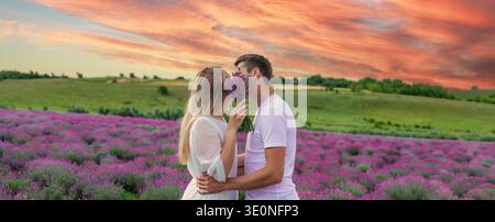 Ein Paar küsst sich in einem Lavendelfeld, versteckt sich hinter einem romantischen Bouquet Stockfoto