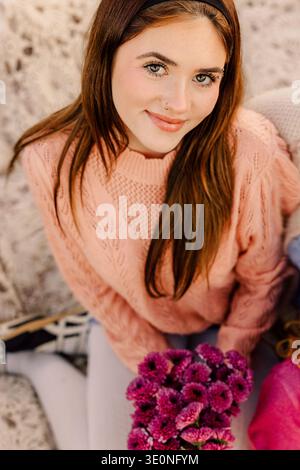 Lächelnde junge Frau mit rosa Blumen Stockfoto