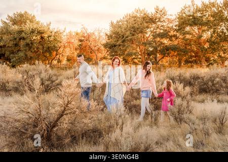 Glückliche Familie, die bei Sonnenuntergang gemeinsam im Freien spaziert Stockfoto