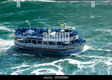 Touristen in blauen Ponchos fahren auf dem Boot Maid of the Mist VI an den Niagarafällen und erleben das berühmte Naturwunder aus nächster Nähe. Stockfoto