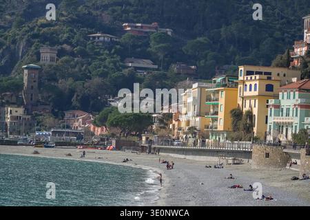 Monterosso al Mare, Cinque Terre, Italien. Farbenfrohe mediterrane Architektur über einem Kiesstrand, wo Sonnenanbeter sich in der Nähe des Ligurischen Meeres entspannen. Stockfoto