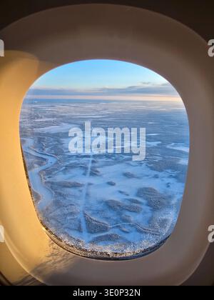 Erleben Sie die bezaubernde Schönheit Lapplands, während eisblaue Seen und weite schneebedeckte Wälder sich endlos unter Ihnen erstrecken. Dieser atemberaubende Blick aus dem Flugzeug fängt den Zauber des Winters in Finnland ein. Stockfoto