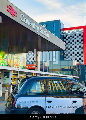 Schwarzes Taxi parkt vor dem modernen Außenbereich des Bahnhofs Coventry mit modernen Gebäuden in der städtischen Umgebung Stockfoto