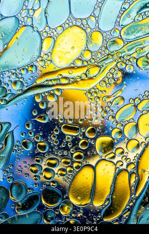 Lebendige abstrakte Komposition aus bunten Öltröpfchen und fließenden Linien, die Blau-, Gelb- und Grüntöne zu einem kreativen organischen Muster verschmelzen. Stockfoto