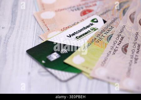 KIEW, UKRAINE - 28. JANUAR 2026 Vietcombank-Karte und vietnamesische Dong-Geldscheine auf dem Tisch in Nahaufnahme. Die Vietcombank ist die beliebteste Bank in Vietnam Stockfoto